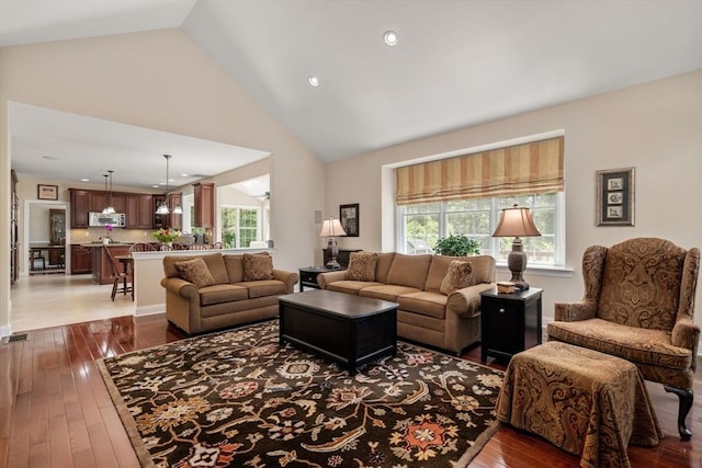 living room with plenty of natural light, hardwood / wood-style floors, high vaulted ceiling, and recessed lighting