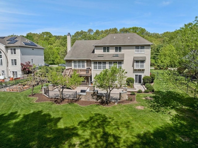 rear view of property featuring a garden, a patio, a chimney, and a wooden deck