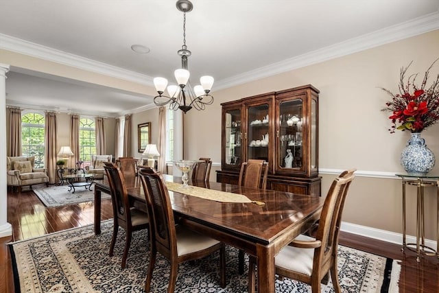 dining space featuring hardwood / wood-style flooring, crown molding, a chandelier, baseboards, and decorative columns