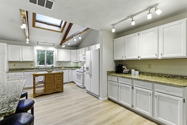 1 New Castle Rd, Ashland, MA 01721 - kitchen featuring white appliances, track lighting, a skylight, decorative backsplash, and vaulted ceiling