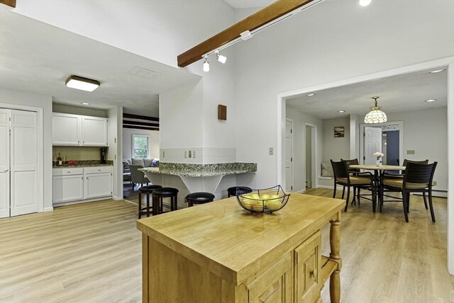 1 New Castle Rd, Ashland, MA 01721 - kitchen with light wood-style floors, a breakfast bar, white cabinetry, recessed lighting, and decorative backsplash