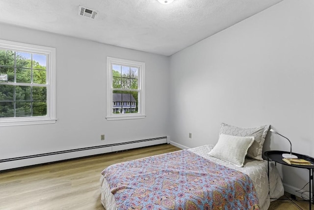 1 New Castle Rd, Ashland, MA 01721 - bedroom with baseboard heating, multiple windows, wood finished floors, and a textured ceiling