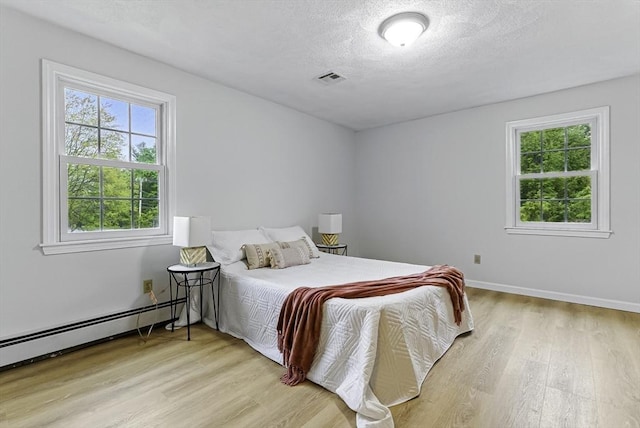 1 New Castle Rd, Ashland, MA 01721 - bedroom with light wood finished floors, multiple windows, a baseboard radiator, a textured ceiling, and baseboards