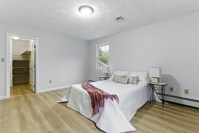 1 New Castle Rd, Ashland, MA 01721 - bedroom featuring light wood-type flooring, a baseboard heating unit, a textured ceiling, and baseboards