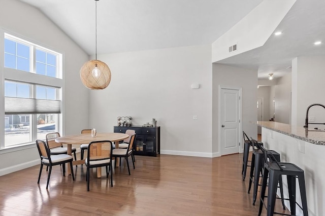 dining room with lofted ceiling, sink, and light hardwood / wood-style floors