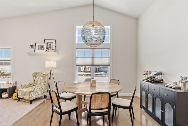 dining area with a notable chandelier, lofted ceiling, and light wood-type flooring