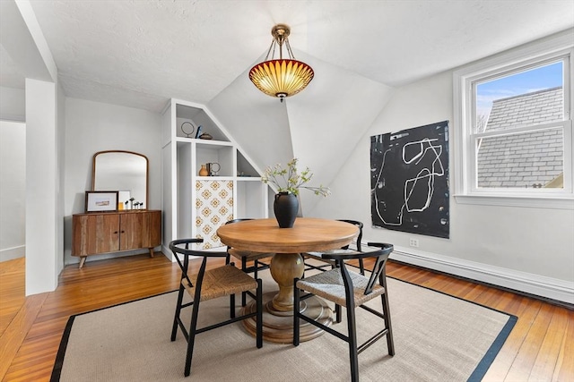 dining space featuring wood-type flooring and lofted ceiling