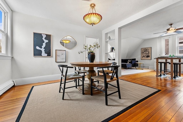 dining room featuring hardwood / wood-style floors, built in features, and a baseboard heating unit