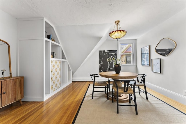 dining room featuring a baseboard heating unit, hardwood / wood-style flooring, and a textured ceiling