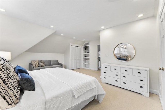 bedroom with vaulted ceiling, light colored carpet, and a closet