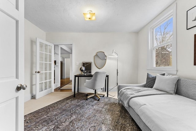 bedroom with carpet floors, a textured ceiling, and french doors