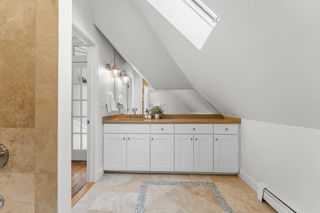 bathroom with a baseboard radiator, lofted ceiling with skylight, and vanity