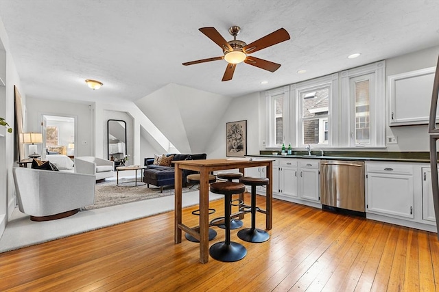 kitchen with sink, plenty of natural light, dishwasher, light hardwood / wood-style floors, and white cabinets