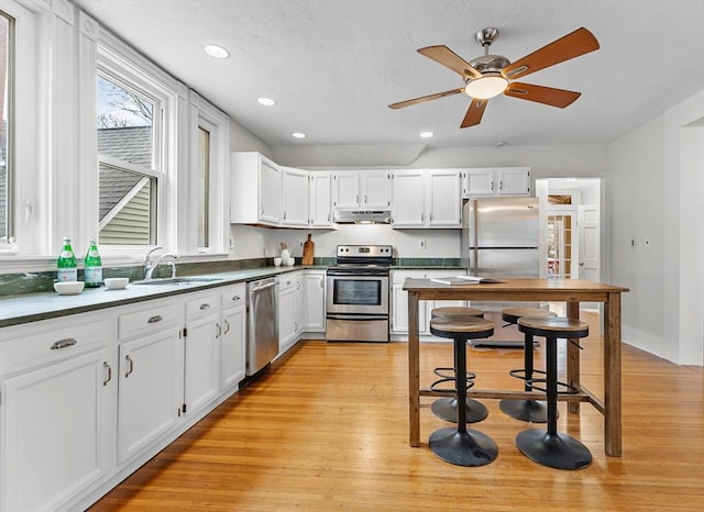 kitchen with white cabinetry, sink, ceiling fan, stainless steel appliances, and light wood-type flooring