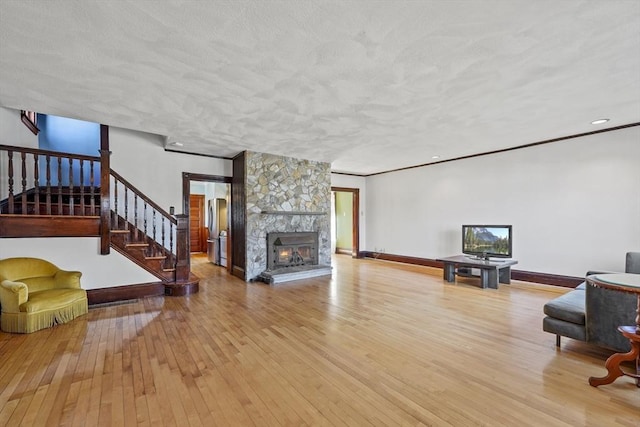 living area featuring stairs, baseboards, wood-type flooring, and a textured ceiling