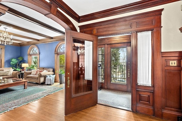 entrance foyer featuring ornamental molding, a notable chandelier, and light hardwood / wood-style flooring