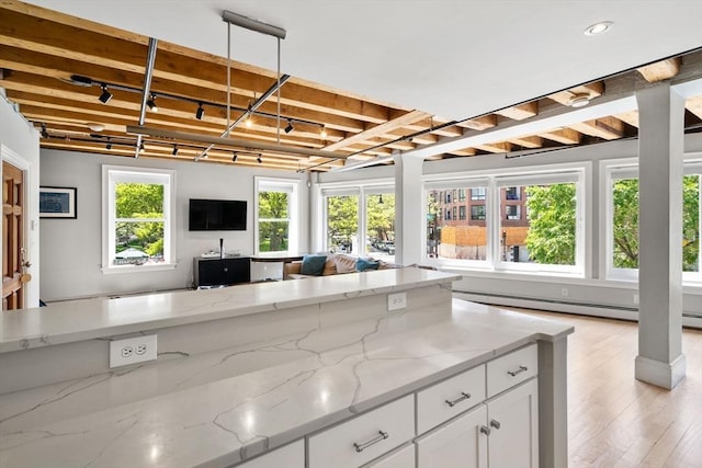 33 Commercial Wharf Unit 33A, Boston, MA 02110 - kitchen with open floor plan, white cabinetry, light stone countertops, beamed ceiling, and baseboard heating