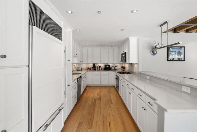 33 Commercial Wharf Unit 33A, Boston, MA 02110 - kitchen featuring appliances with stainless steel finishes, a peninsula, white cabinetry, light stone countertops, and a sink