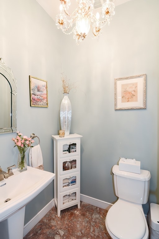 bathroom featuring toilet, a notable chandelier, and sink