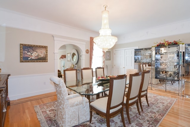 dining area featuring light wood-type flooring, crown molding, and a notable chandelier