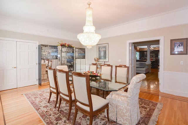 dining area featuring light wood-type flooring, ornamental molding, and a chandelier