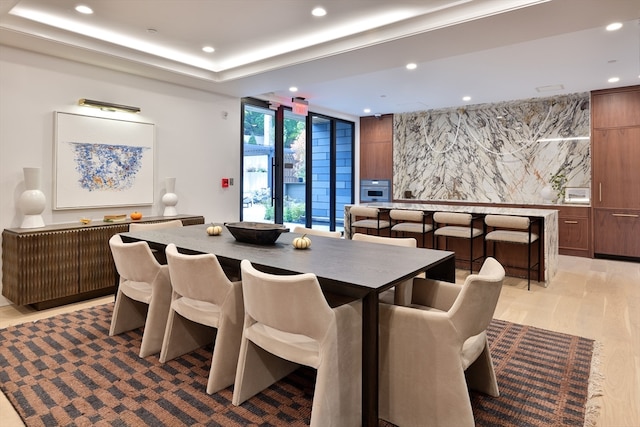 dining room with expansive windows, a tray ceiling, and light hardwood / wood-style floors