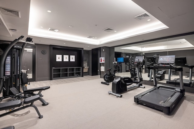 gym with carpet floors and a tray ceiling