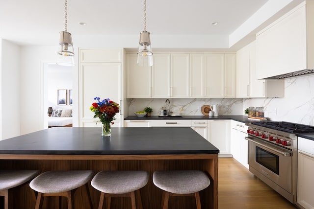 kitchen with a kitchen island, decorative light fixtures, luxury range, and light wood-type flooring