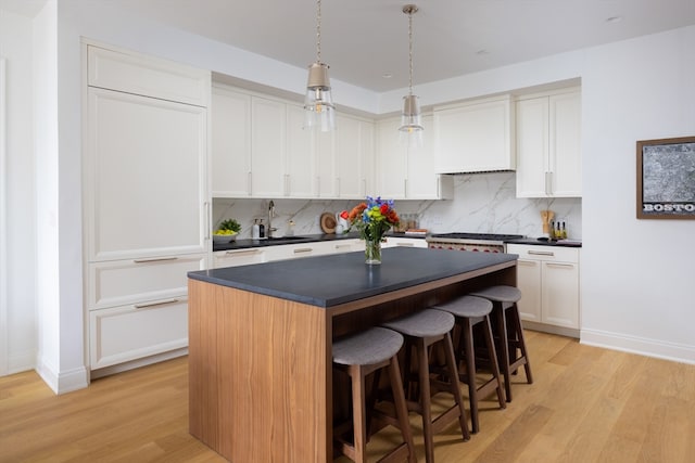 kitchen featuring decorative backsplash, light hardwood / wood-style floors, and white cabinetry