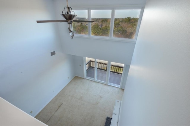 interior space featuring light colored carpet, a high ceiling, and a wealth of natural light