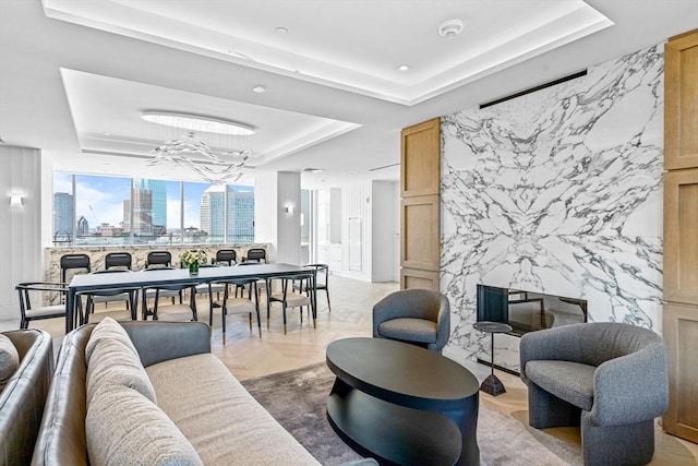 living area with an accent wall, a view of city, and a raised ceiling