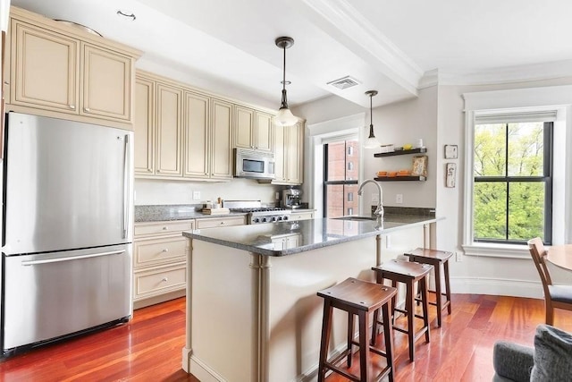 kitchen featuring cream cabinets, stainless steel appliances, dark wood finished floors, ornamental molding, and a sink