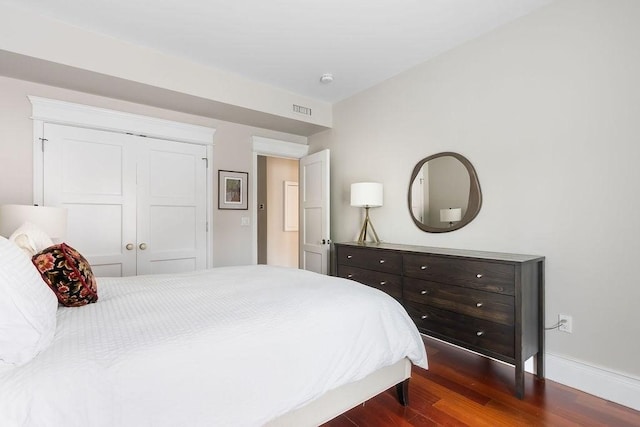 bedroom featuring dark wood-style floors, baseboards, and a closet
