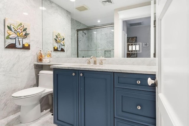 bathroom with a stall shower, toilet, tile walls, vanity, and marble finish floors