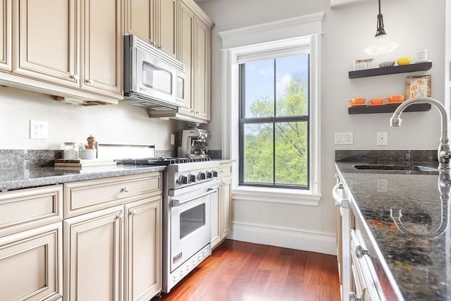 kitchen featuring stainless steel microwave, a sink, cream cabinetry, and gas range