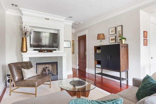 living room featuring wood finished floors, a tile fireplace, ornamental molding, recessed lighting, and baseboards