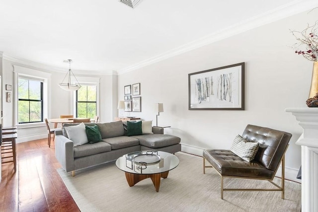 living area with crown molding, hardwood / wood-style floors, and baseboards