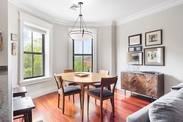 dining room with wood finished floors, crown molding, and baseboards