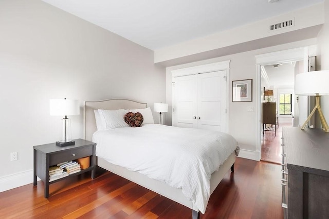 bedroom featuring dark wood-style floors, baseboards, and a closet