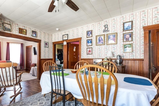 dining space featuring ceiling fan, a wainscoted wall, wood finished floors, and wallpapered walls