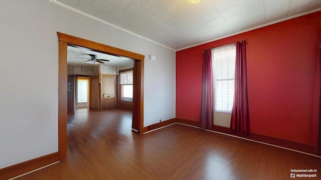 spare room with a healthy amount of sunlight, wood finished floors, baseboards, and ornamental molding