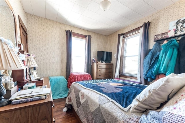 bedroom featuring wallpapered walls and wood finished floors