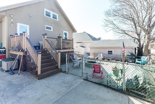 back of property featuring a deck, a gate, fence, a fire pit, and a patio area