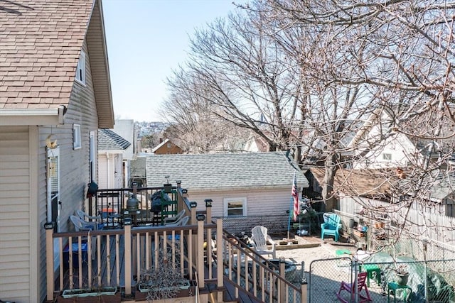 exterior space with a deck, roof with shingles, and fence