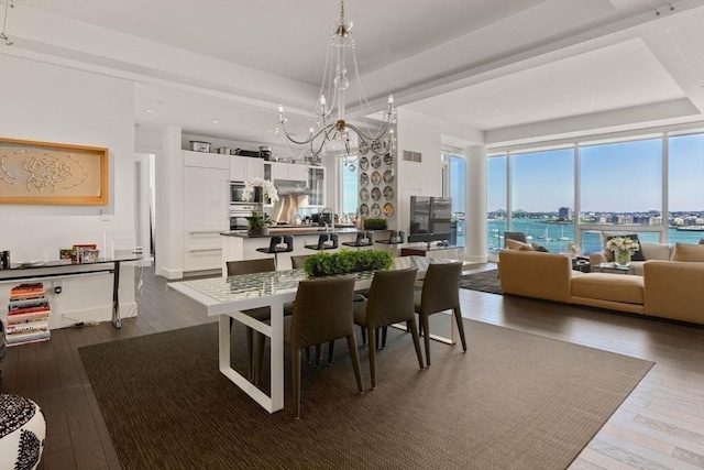 dining space with a water view, dark wood-type flooring, and a notable chandelier