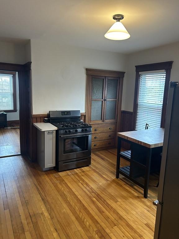 29 Tatman St, Worcester, MA 01607 - kitchen with gas range, freestanding refrigerator, wainscoting, light wood-type flooring, and plenty of natural light