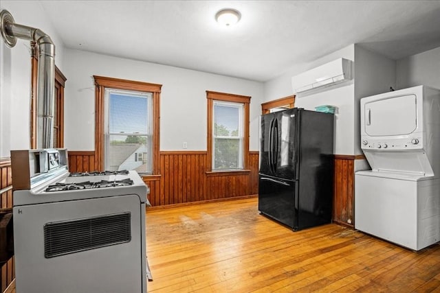 29 Tatman St, Worcester, MA 01607 - kitchen with freestanding refrigerator, wainscoting, stacked washer and clothes dryer, light wood-type flooring, and gas range gas stove