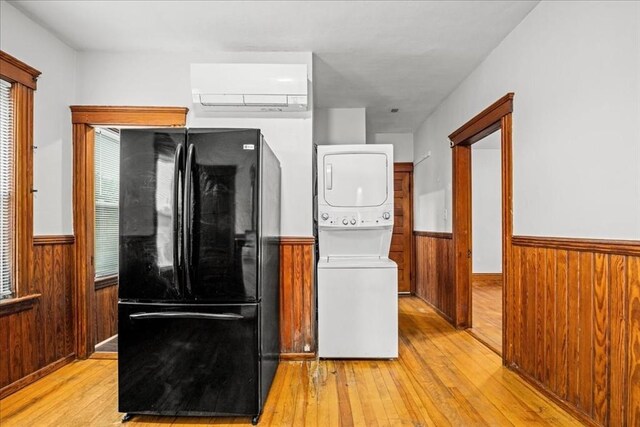 29 Tatman St, Worcester, MA 01607 - kitchen featuring freestanding refrigerator, stacked washing machine and dryer, a wall mounted air conditioner, a wainscoted wall, and light wood-style floors