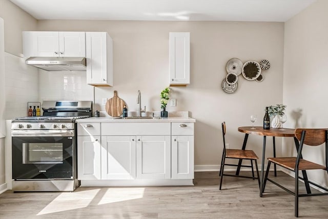 45 Stanley St, Lowell, MA 01850 - kitchen with gas stove, under cabinet range hood, light wood-style flooring, and white cabinetry