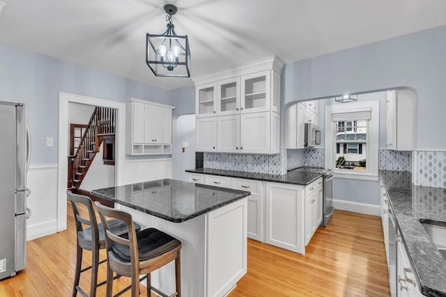 kitchen featuring hanging light fixtures, white cabinets, light hardwood / wood-style floors, a kitchen island, and appliances with stainless steel finishes